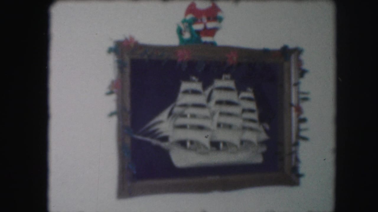 1959 Kansas City frame of a white sailing ship cutout on a dark blue background, with red and green holiday trim and a Santa figure above.