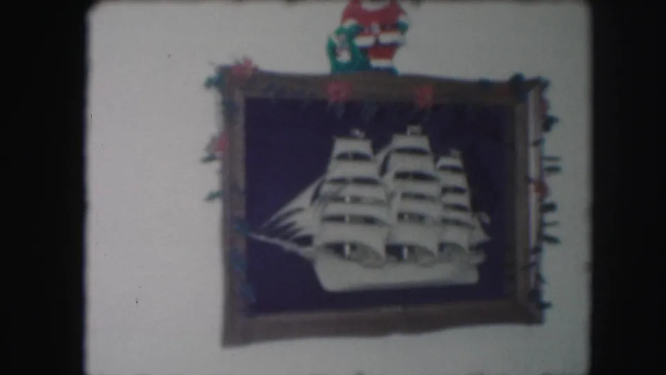 1959 Kansas City home-movie frame showing the decorated framed ship more closely, with ornaments around the frame and a Santa figure at the top.