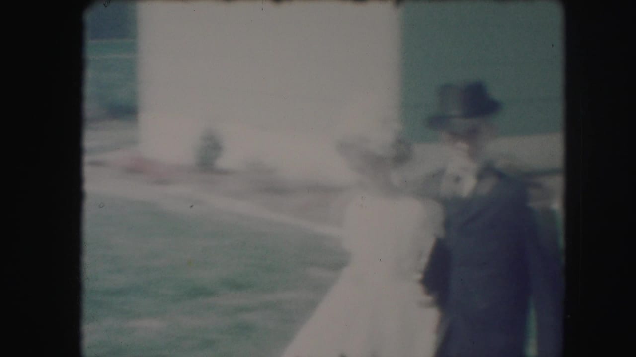 The boy in formal clothes appears to guide the girl in a white dress through a Kansas City suburban yard.