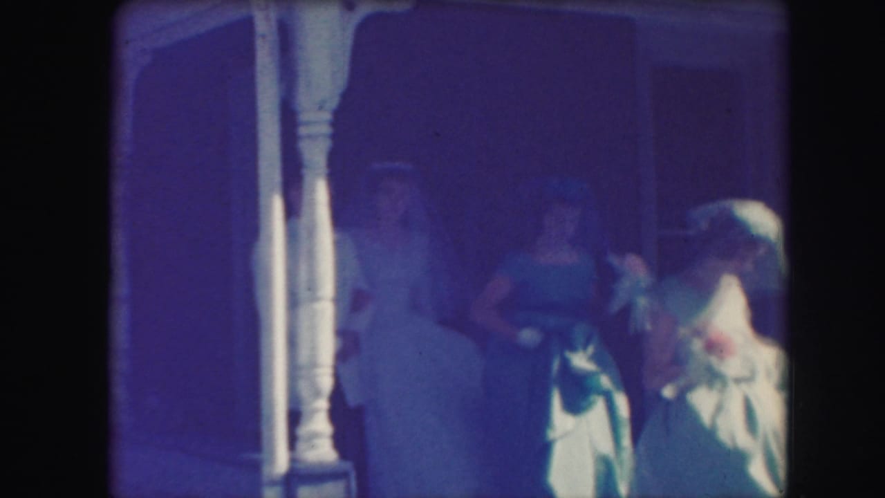 1959 Kansas City wedding party on a porch, with blue dresses, white veil, bouquets, and shaded doorway visible.
