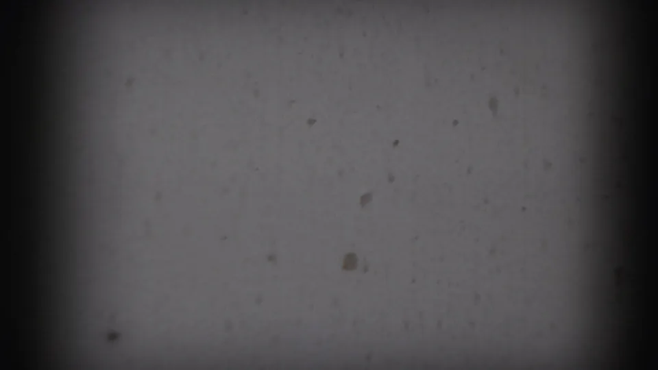 Dim opening frame from a 1959 8mm home movie, showing mostly dark gate shadow and a faint wall surface.