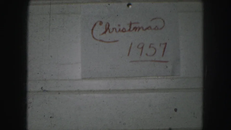 The handwritten “Christmas 1957” title sits lower in the 8mm frame, with muted color, grain, and a dark border at the edge.