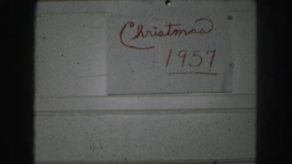 Kansas City 8mm home-movie frame showing the red underlined “Christmas 1957” inscription with dust, grain, and slight exposure softness.