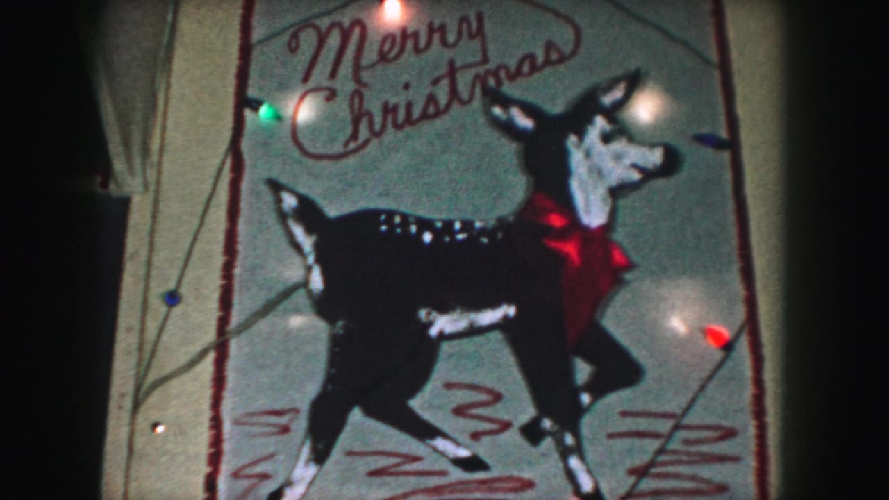 Painted reindeer with a red bow under cursive Merry Christmas text and colored bulbs.