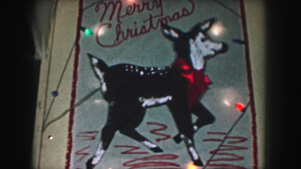 1959 Kansas City frame of a black-and-white reindeer Christmas decoration with cursive text and glowing bulbs.