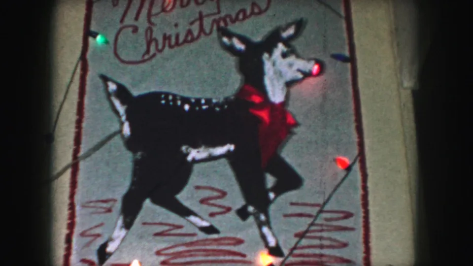 1959 Kansas City home-movie still showing the reindeer design closer in frame with Merry Christmas text partly visible.