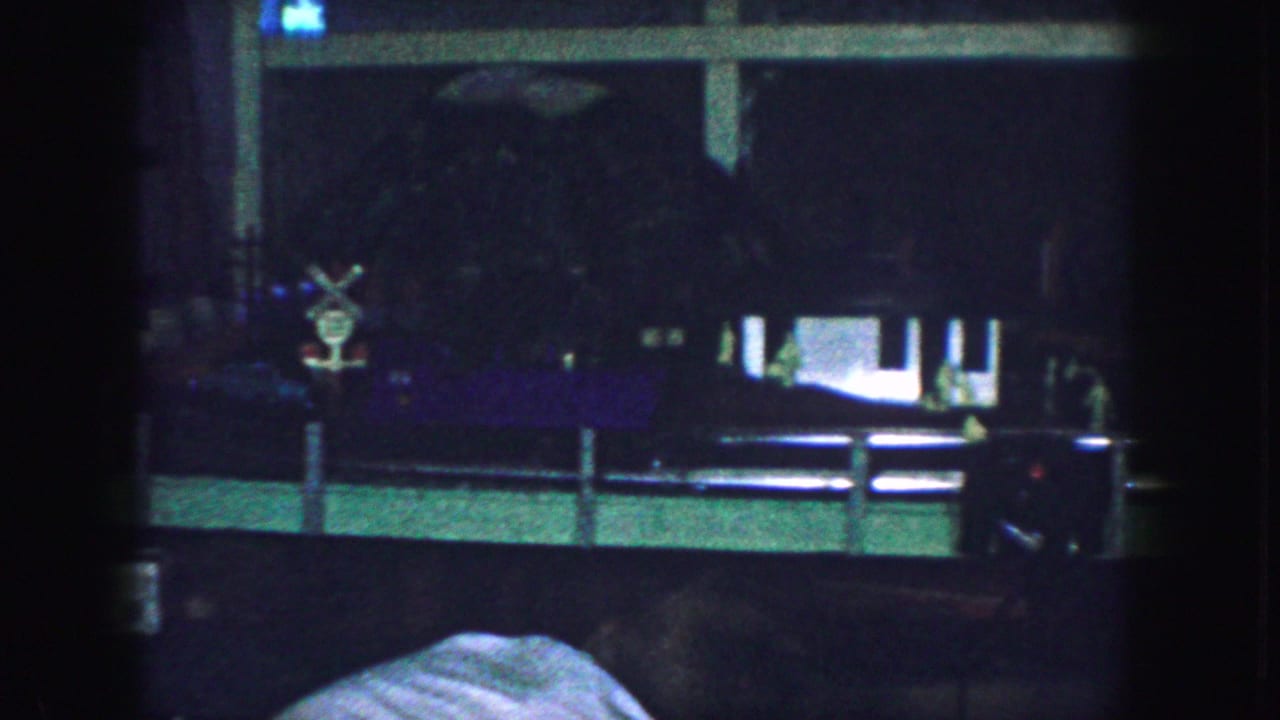 Dim interior view with a dark window or television area and furniture partly visible.