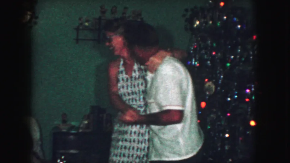 The couple continues dancing close together beside the Christmas tree in a 1959 Kansas City home interior.