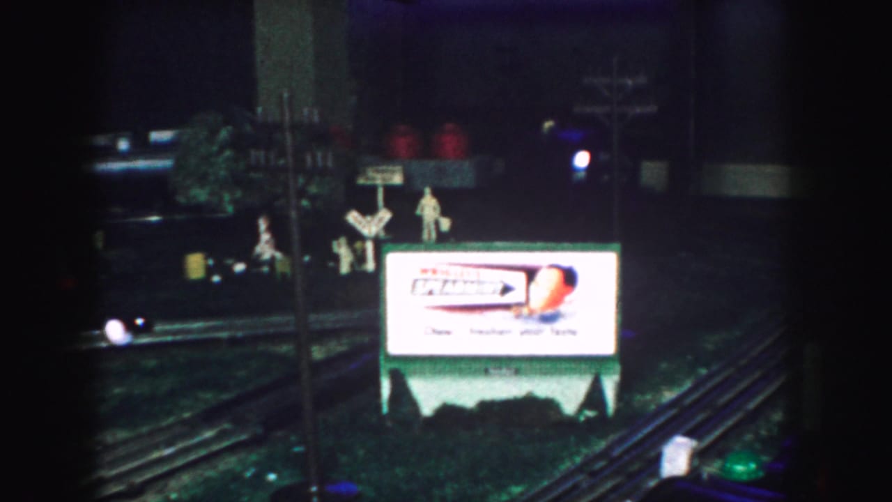 A 1959 Kansas City home-movie frame shows model railroad tracks with a Wrigley's Spearmint sign and small display figures.