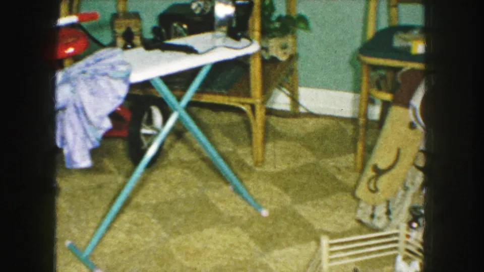 1959 Kansas City domestic scene showing an ironing board with clothing near a Western toy display and mid-century household furniture.