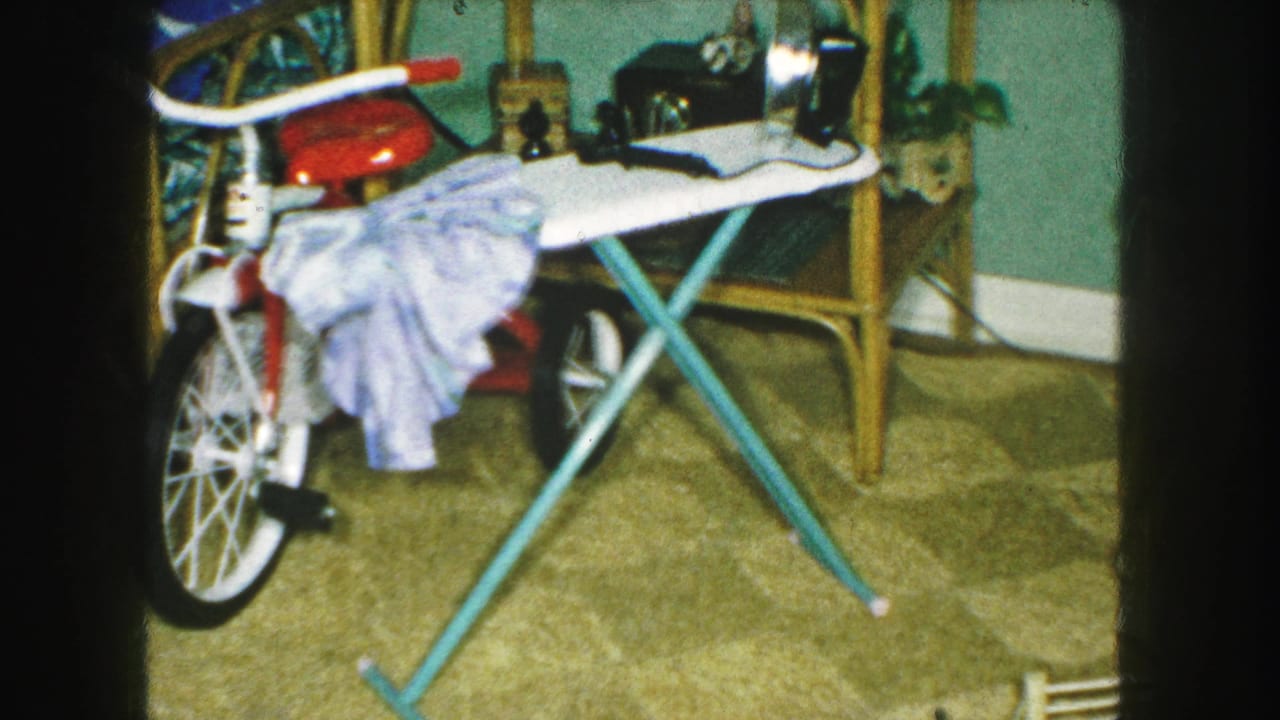 1959 Kansas City home interior with a red tricycle, ironing board, blue garment, and holiday decorations partly visible.