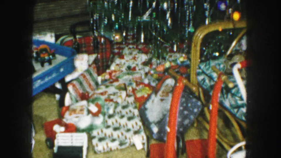 1959 Kansas City holiday interior showing wrapped gifts, toys, a blue wagon, a red tricycle, and shiny tinsel overhead.