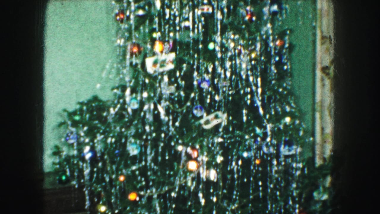 Upper portion of a Christmas tree with tinsel, ornaments, lights, and a star topper.
