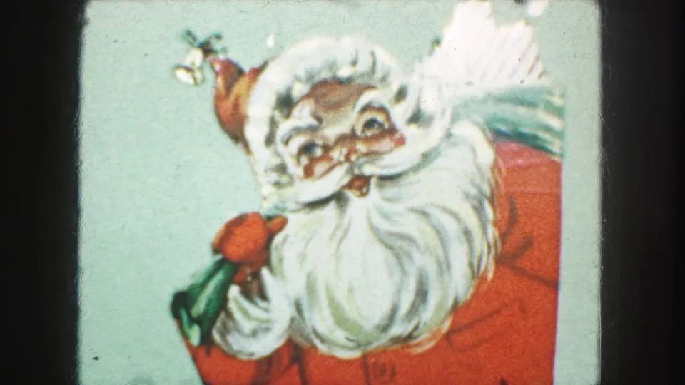 Home-movie frame of the Santa holiday card, tightly cropped with the illustrated beard, red suit, and green bag visible.