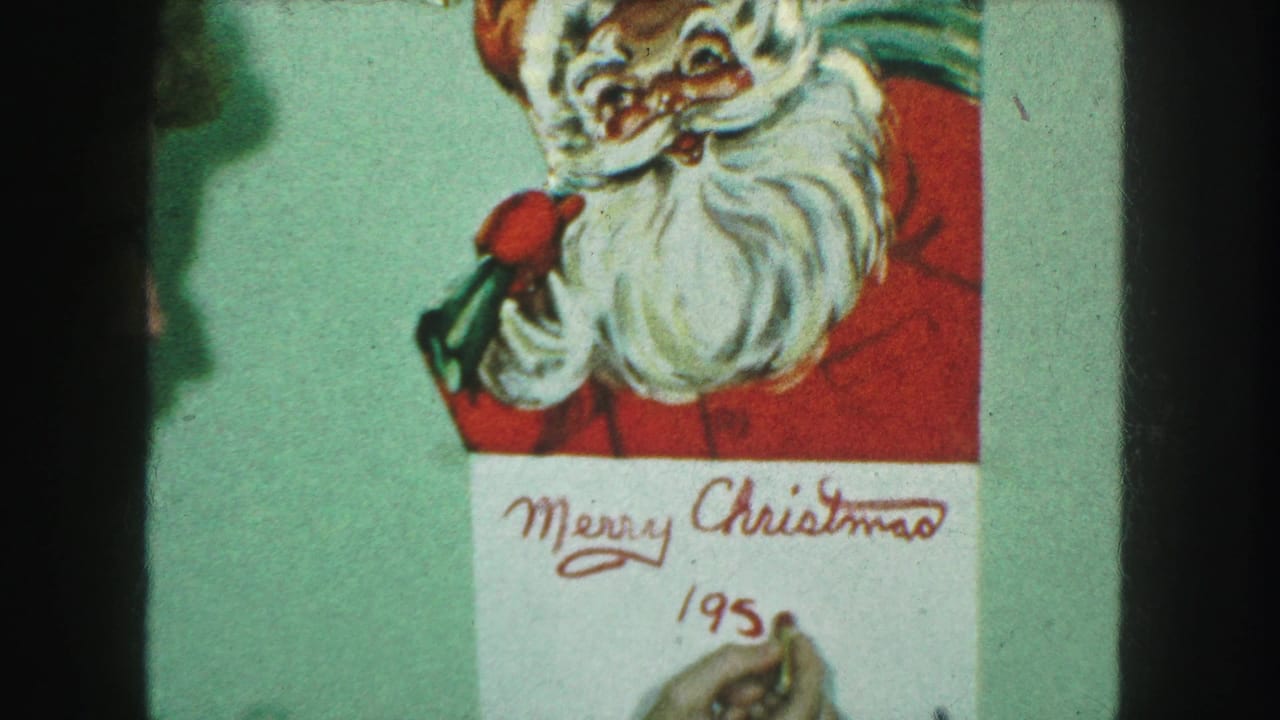Close 8mm view of a Santa Christmas card with red handwriting as the 1959 date is being added below the greeting.