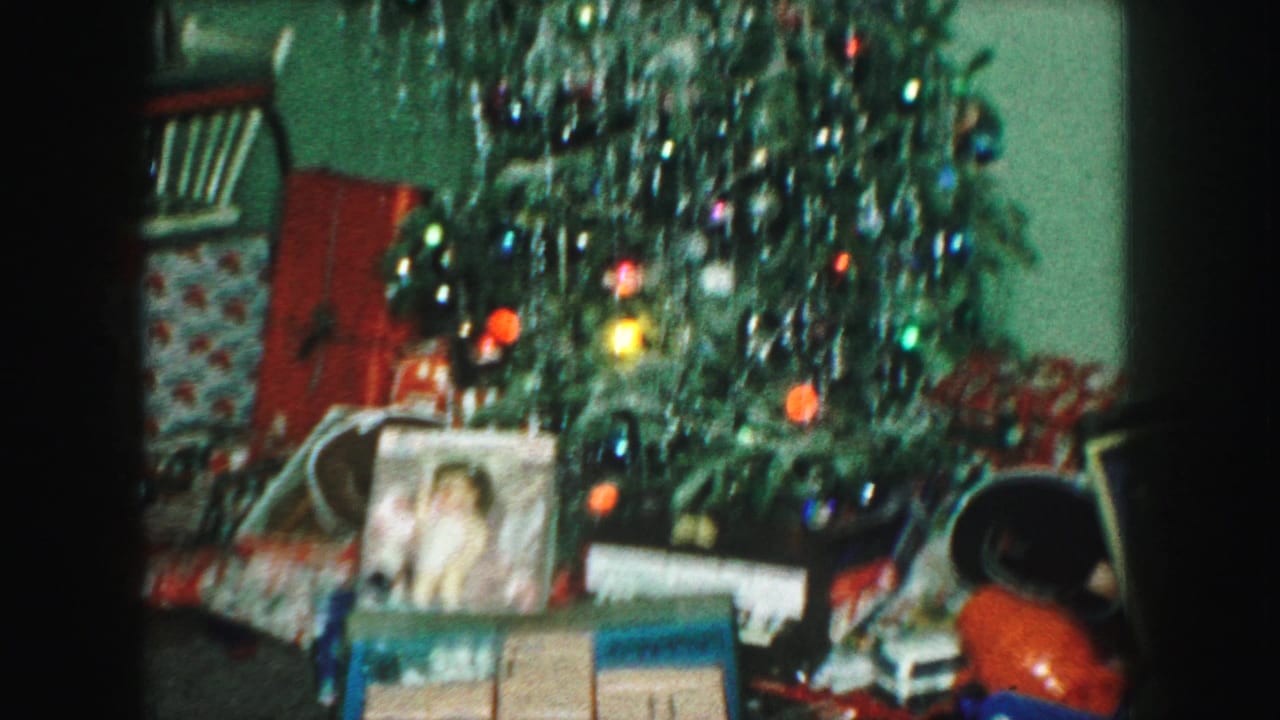 Tinsel-covered Christmas tree with wrapped presents and a framed photograph below.