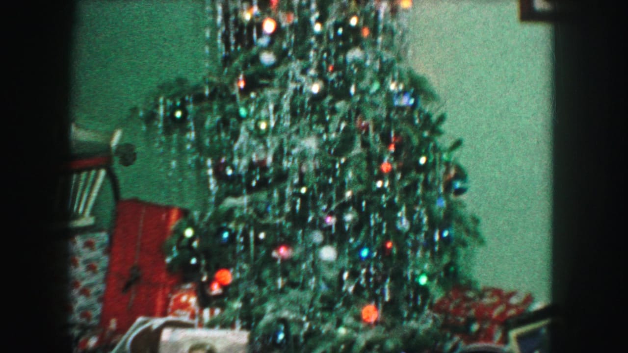 1959 Kansas City interior view of a Christmas tree thick with silver tinsel, colored ornaments, and partially visible presents below.