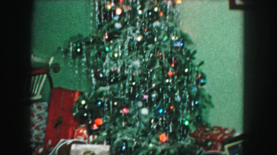 1959 Kansas City interior view of a Christmas tree thick with silver tinsel, colored ornaments, and partially visible presents below.