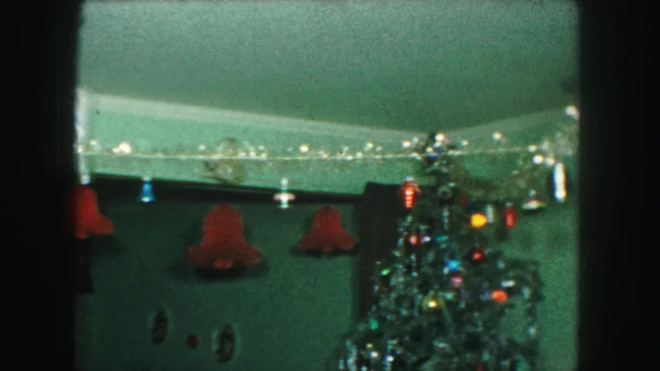 1959 Kansas City frame with a decorated Christmas tree, shiny ornaments, wall garland, and hanging bell decorations inside a private home.