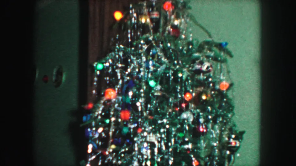 1959 Kansas City home-movie view of the Christmas tree as the camera moves along its tinsel-covered branches and colored lights.