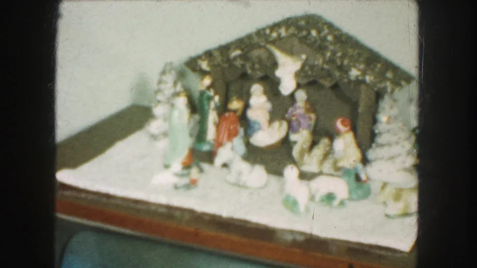 Soft 8mm view of a Kansas City Christmas nativity arrangement with ceramic figures, a stable roof, and white decorative trees.