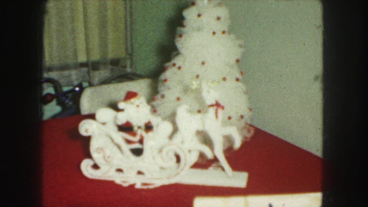 1959 Kansas City home-movie frame of a white Santa sleigh display and small white tree with red ornaments or dots.