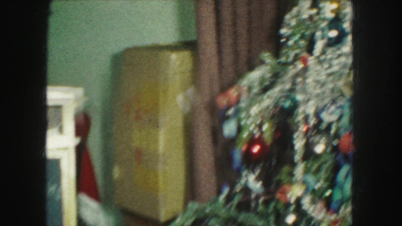 Kansas City holiday interior with a decorated artificial Christmas tree, tinsel, ornaments, brown curtains, and a floor lamp.
