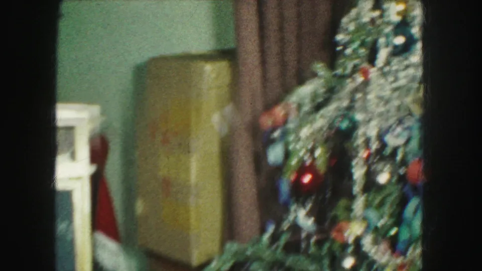 Kansas City holiday interior with a decorated artificial Christmas tree, tinsel, ornaments, brown curtains, and a floor lamp.