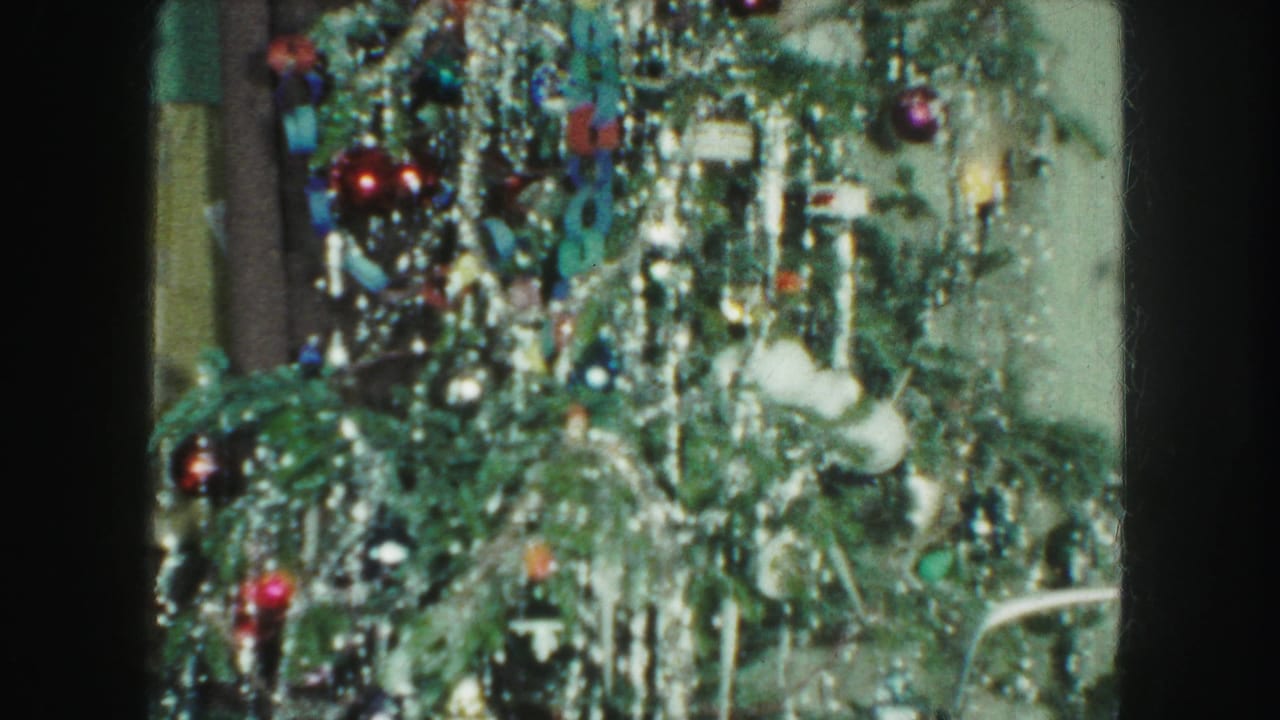 1959 Kansas City home-movie frame showing a Christmas tree with dense tinsel, colored ornaments, and lights in a private interior.