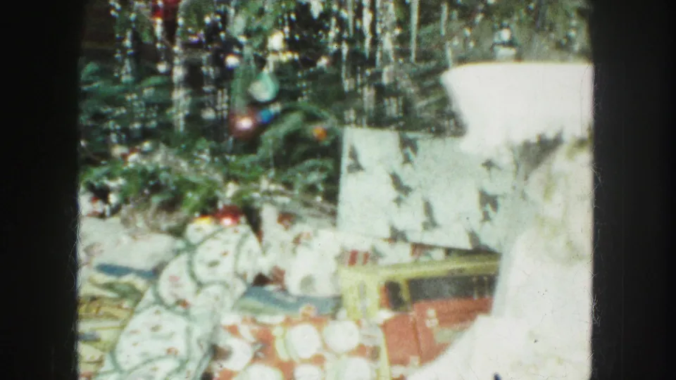 1959 Kansas City home-movie view of wrapped presents, ribbons, ornaments, and hanging tinsel under a Christmas tree.
