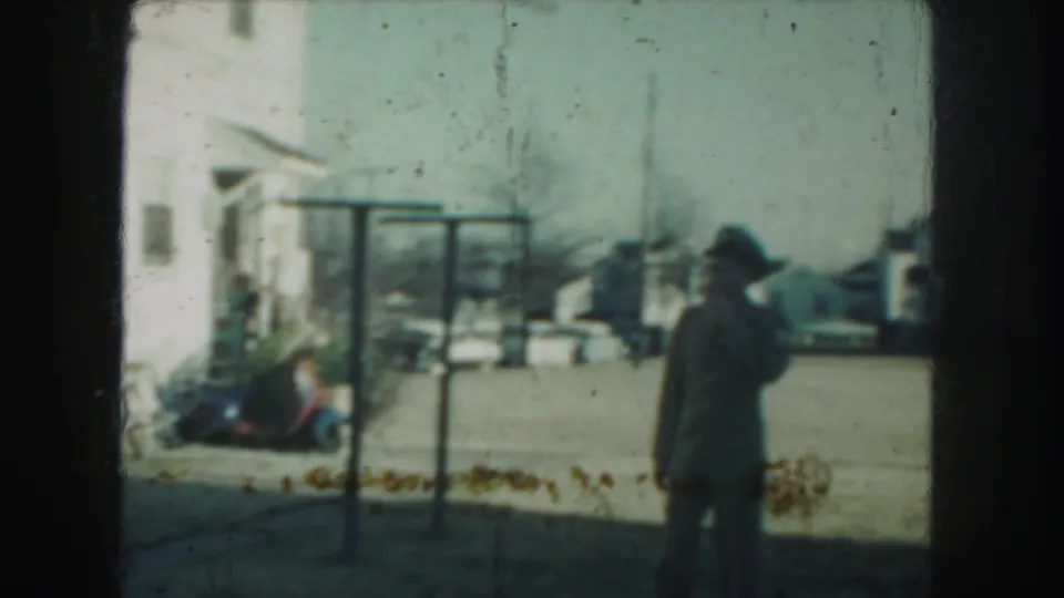 At the end of the 1959 Kansas City clip, the uniformed man turns slightly aside with his hand near his face in the yard.