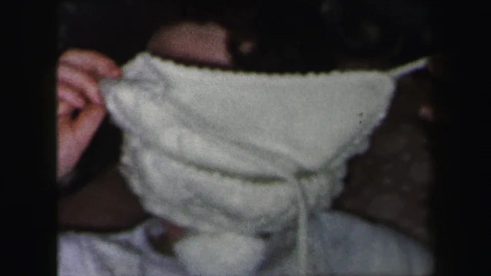 Lynbrook, New York 1975 frame of a young woman close to the camera, her face mostly covered by a white knitted hat.