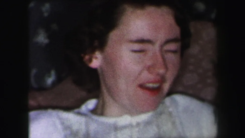 The young woman appears in a close 1975 Lynbrook interior shot, smiling as the white fabric drops from her face.