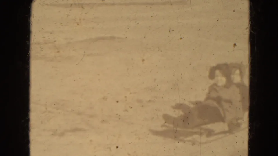 Soft 8mm frame of bundled young people on or near a sled in snowy Lincoln, Nebraska home-movie footage.