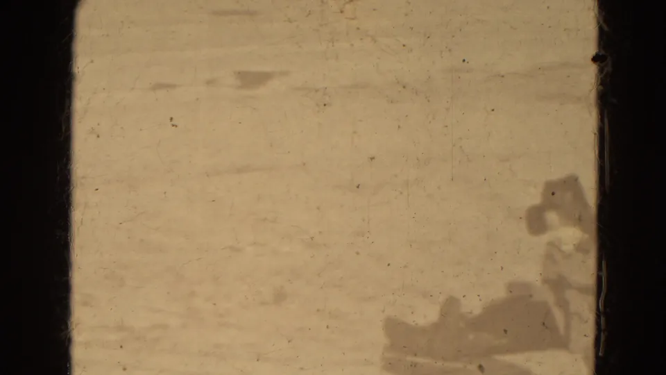 Distant 8mm view of bundled figures with a sled near the edge of a snowy Lincoln, Nebraska scene.