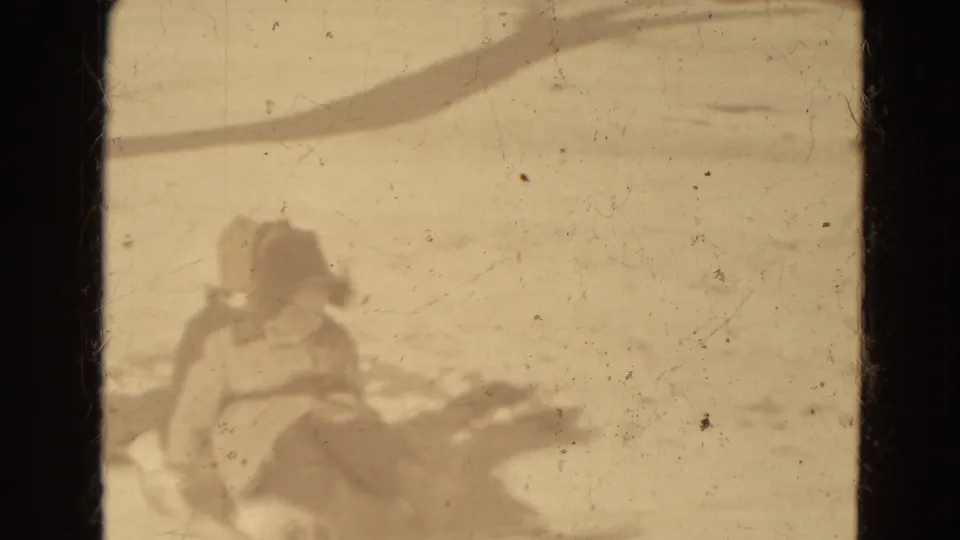 A small bundled figure sits near a sled in a snowy open area, seen in soft 1942 home-movie footage from Lincoln.