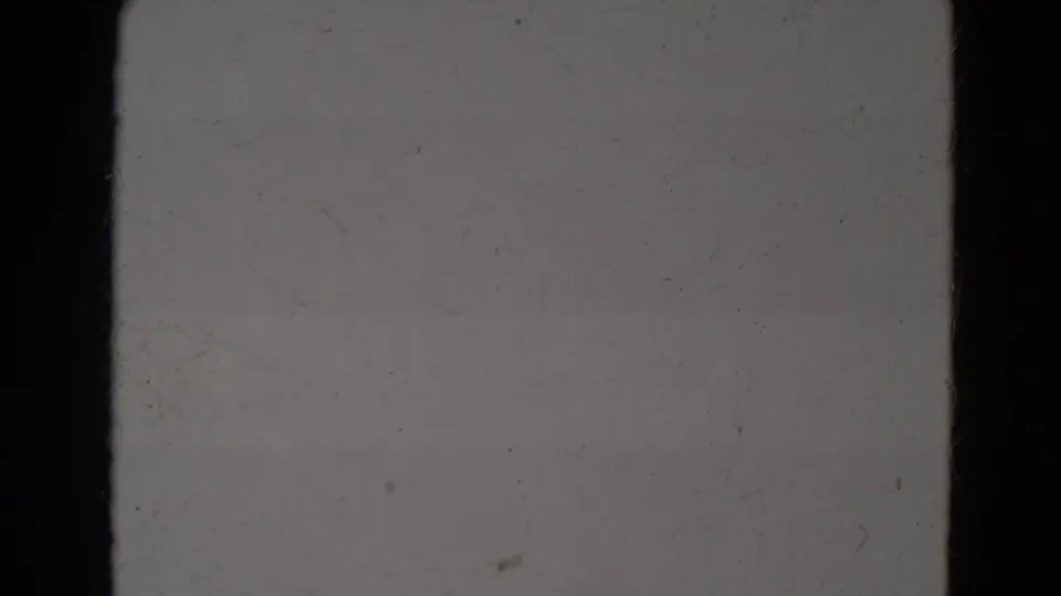 Static gray 8mm frame from the supplied Lincoln, Nebraska clip metadata, showing blank film texture, dust, scratches, and dark vertical edges.