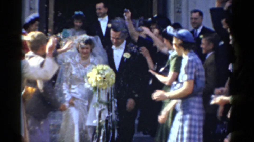 1975 Bridgeport wedding footage shows the bride and groom exiting as guests throw confetti or bird seed around them.