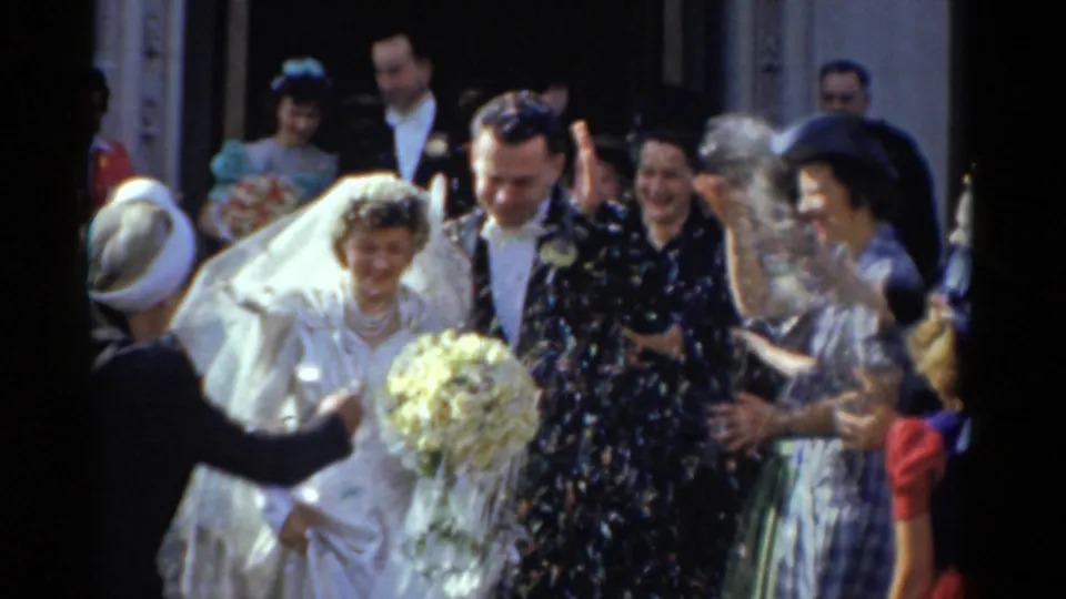 1975 Bridgeport wedding exit with the bride holding a yellow bouquet while guests smile and throw confetti or seed.
