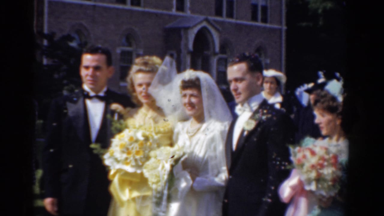 Bride and groom with attendants standing outside a brick church.
