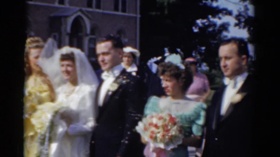 Bride and groom stand with attendants outside a brick church during a 1975 Bridgeport wedding home movie.