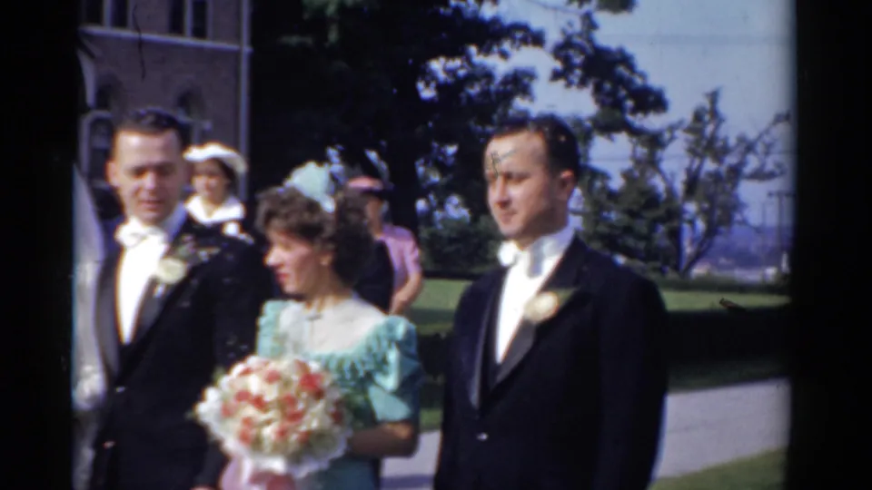 Wedding attendants move across the church lawn in Bridgeport, with a bridesmaid carrying a bouquet beside tuxedoed men.