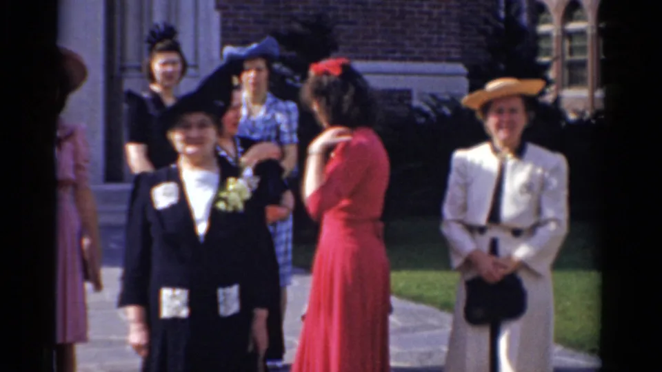 Guests in dresses, hats, and formal clothing stand outside the Bridgeport church at the end of the wedding clip.