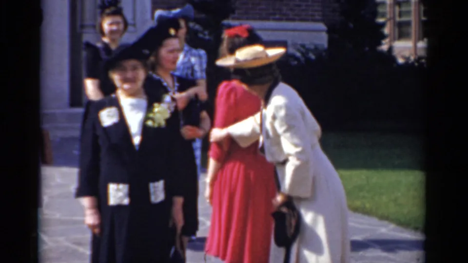 Women interact and pose outdoors in a 1975 Bridgeport 8mm home-movie scene near a brick building.