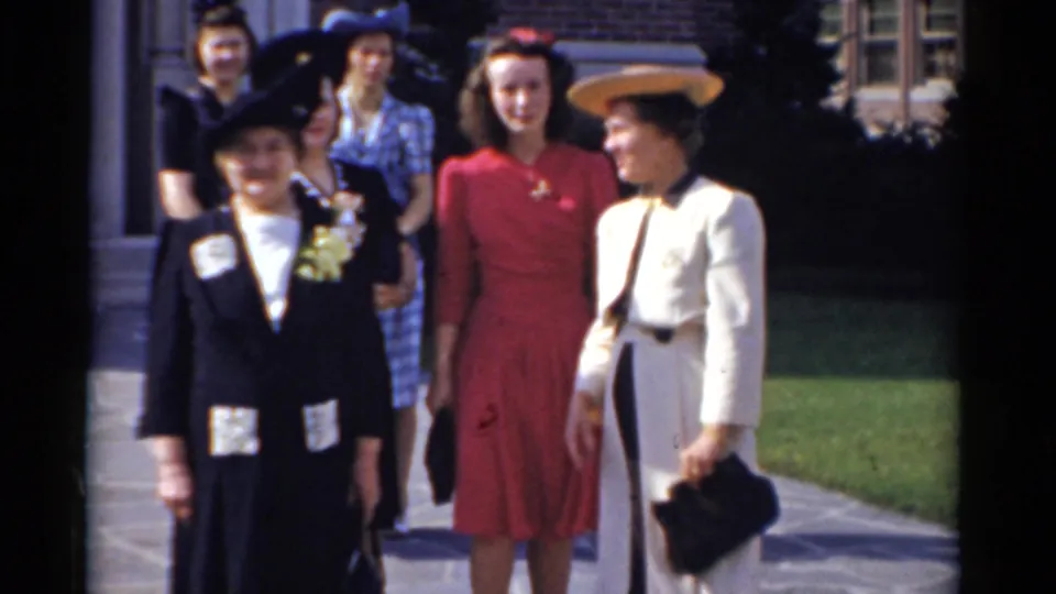 Women in 1970s formal attire stand in sunlight outside a Bridgeport brick building.
