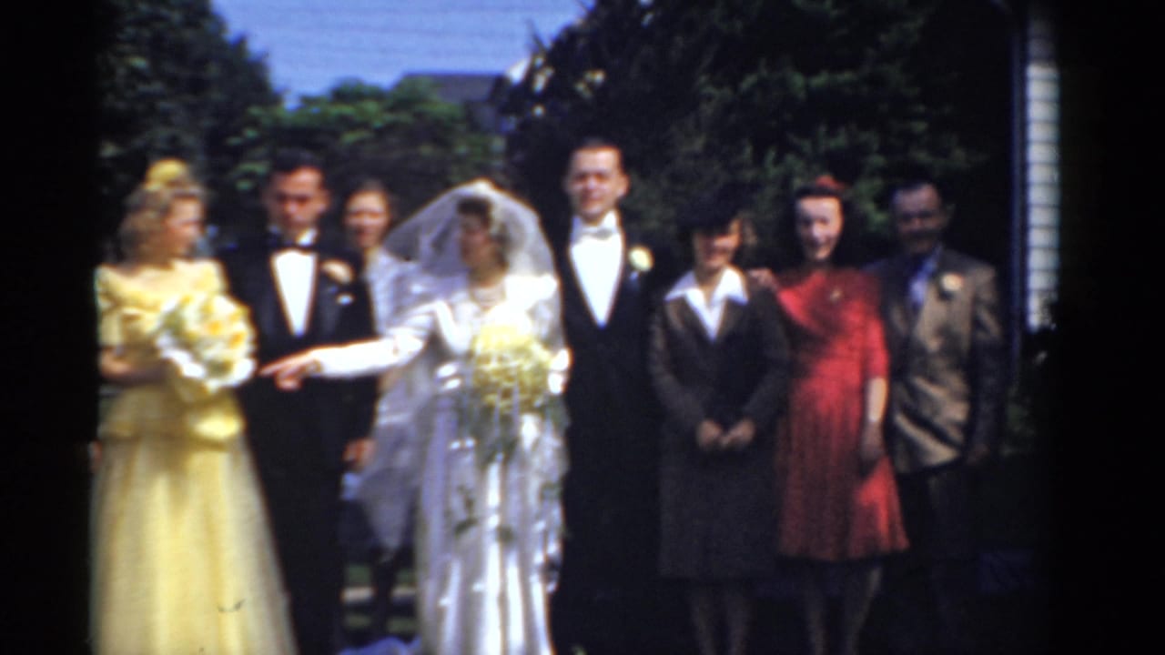 1975 Bridgeport wedding party poses outdoors, with a bride in a white gown and veil beside a groom in a tuxedo and guests in colorful formalwear.