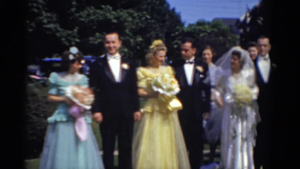The Bridgeport wedding party continues posing outdoors in 1975, with the bride in white, a woman in yellow, tuxedoed men, and a young attendant visible.