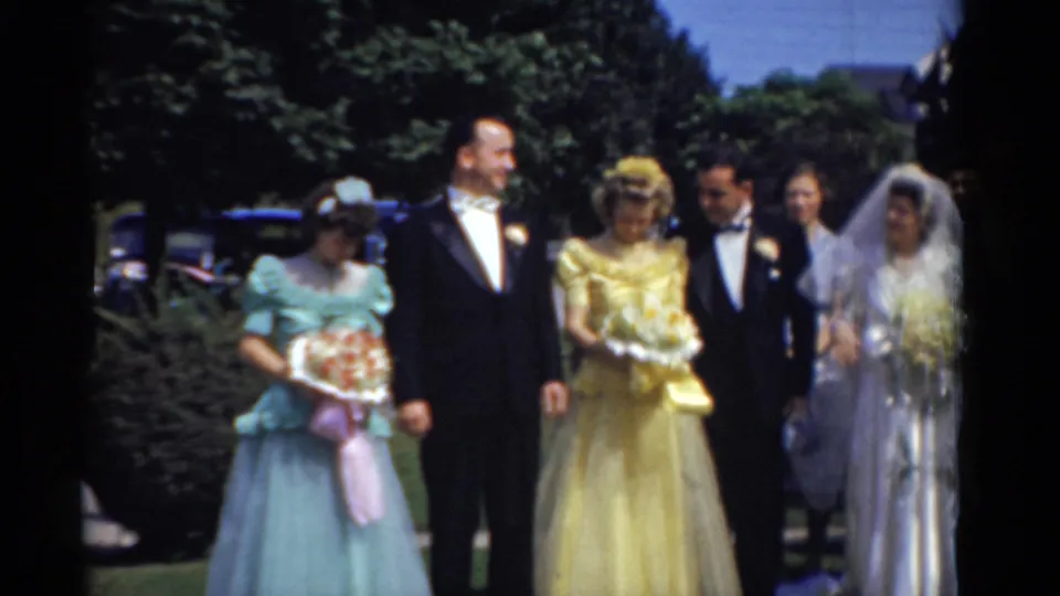 1975 Bridgeport wedding party posing outdoors, with bridesmaids in blue and yellow, men in tuxedos, and the bride in a white veil.
