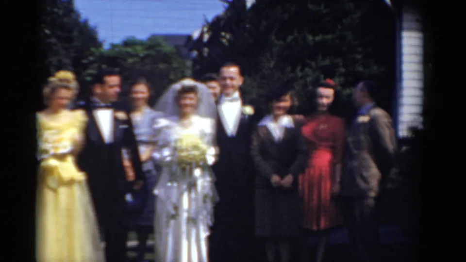 1975 Bridgeport wedding group outdoors, with the bride and groom centered among guests in yellow, dark, and red formal clothing.