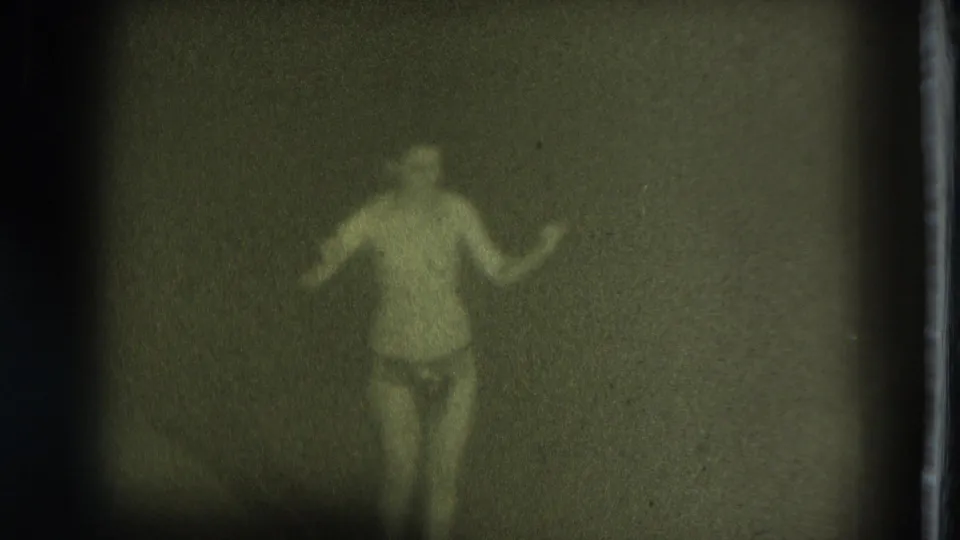 1975 San Francisco home-movie frame of an adult woman dancing in soft focus, with grain, green tint, and little background detail.